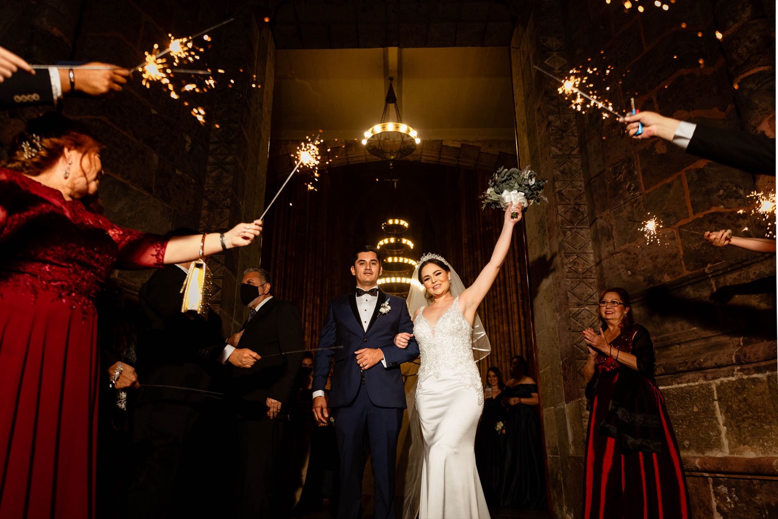Salida de los novios entre luces de bengala sostenidas por los invitados