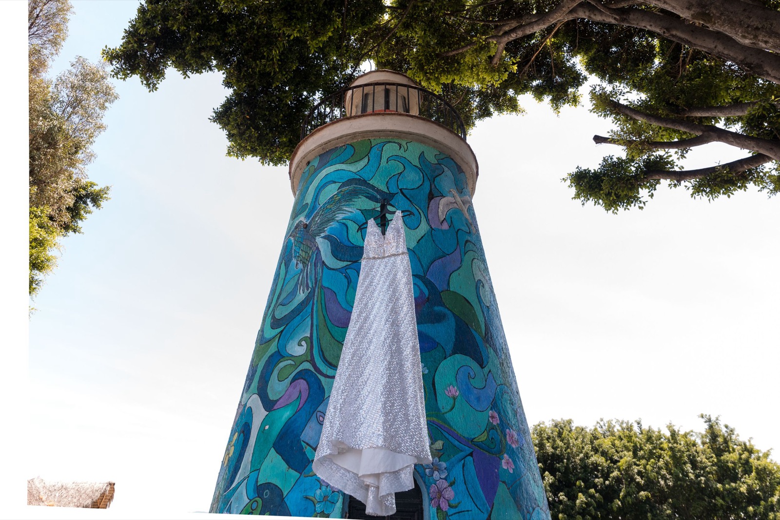 Vestido de novia colgado de un faro pintado con un mural azul