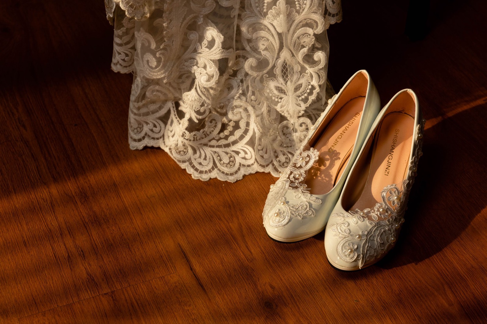 Zapatos de novia y encaje del vestido en la luz de la ventana