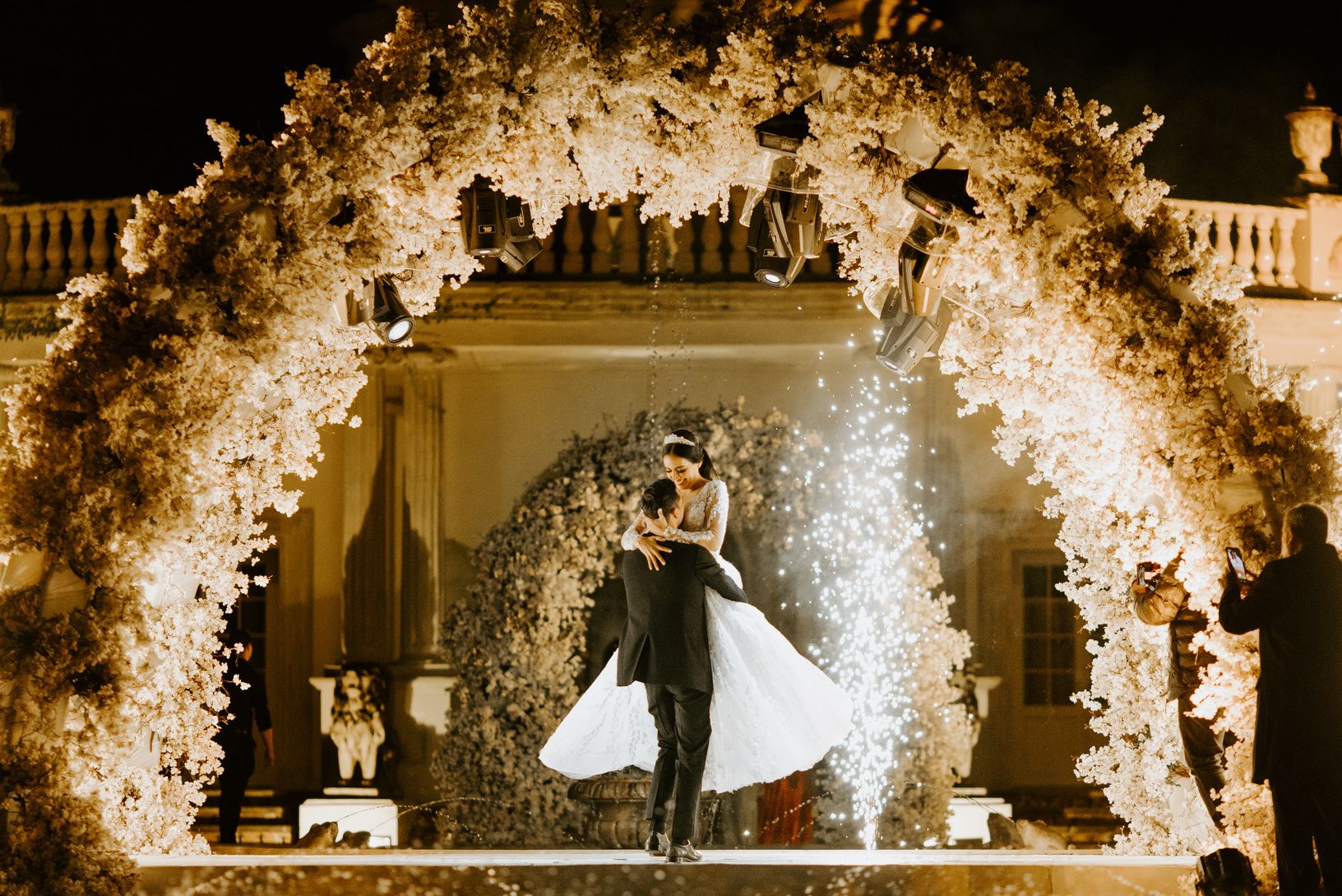 Los novios bailan bajo un arco de flores iluminado