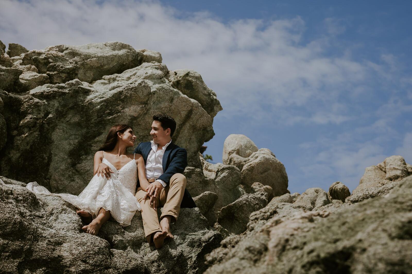 Los novios abrazados entre rocas junto al mar