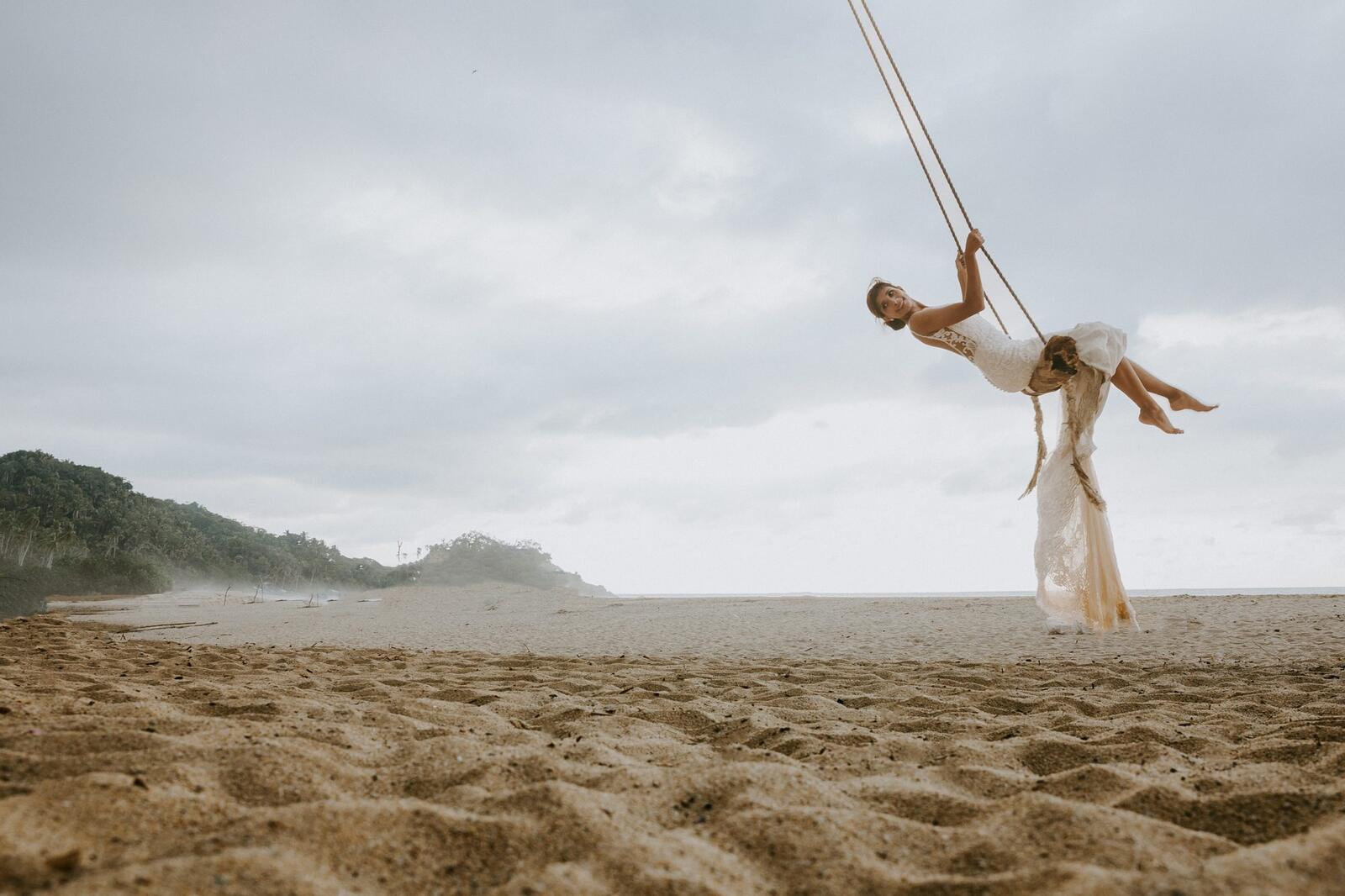 La novia en un columpio sobre la arena de la playa