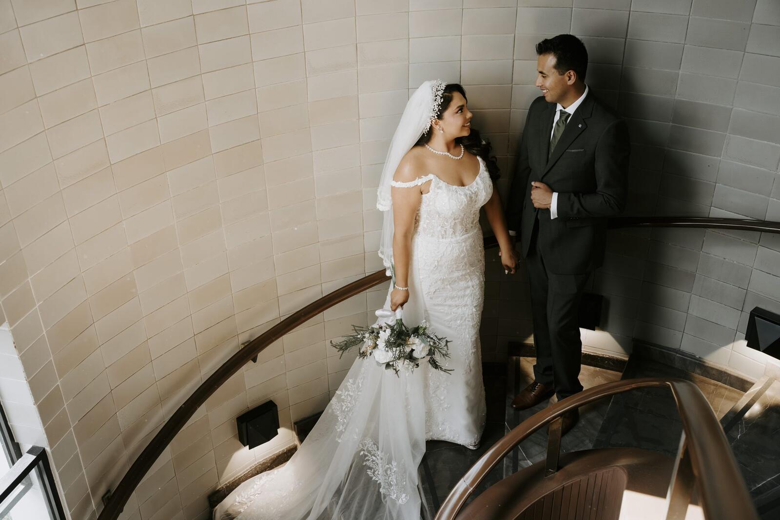 Los novios en una escalera de caracol de muros claros