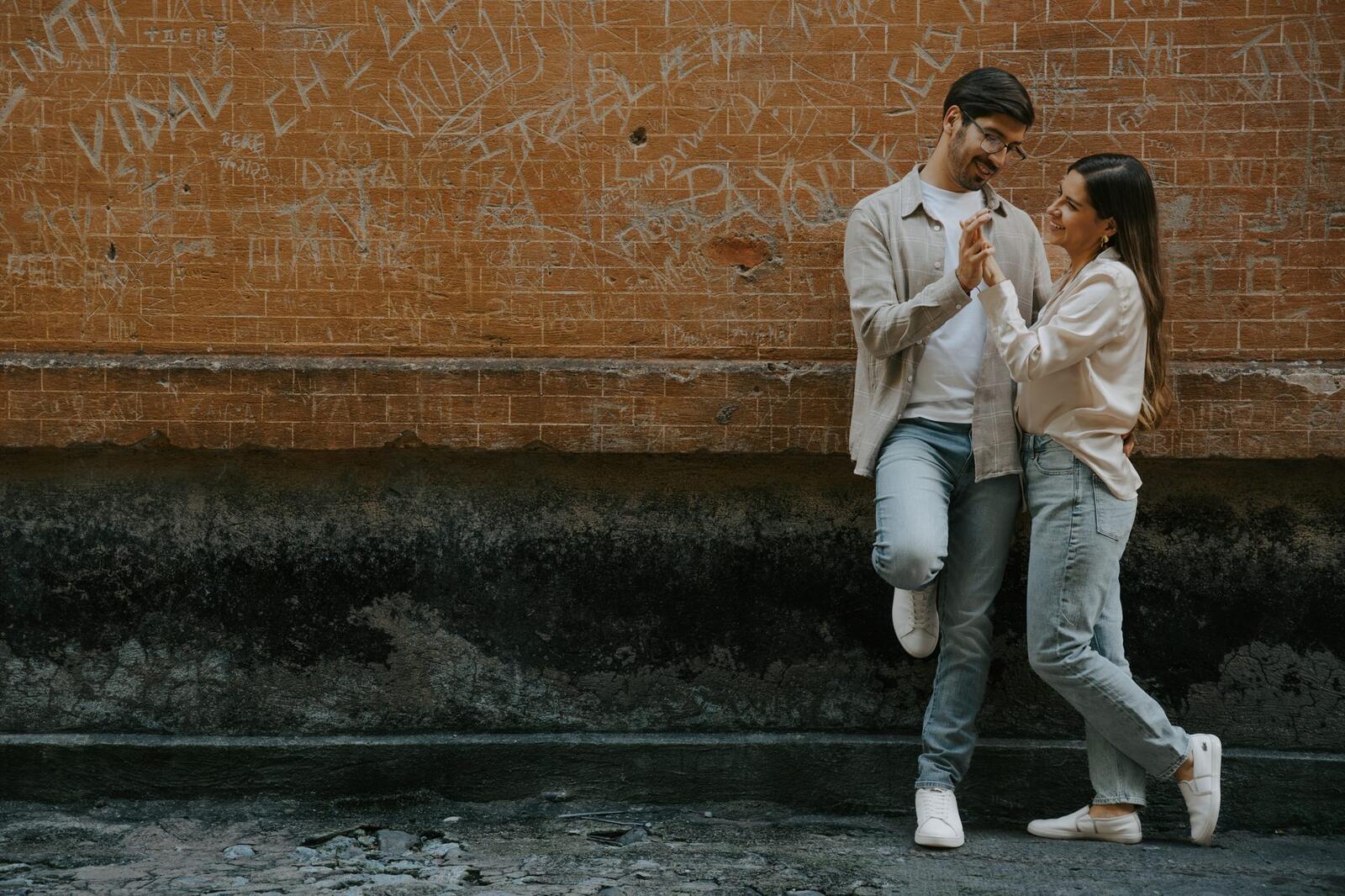 La pareja abrazada recargada en un muro de ladrillo