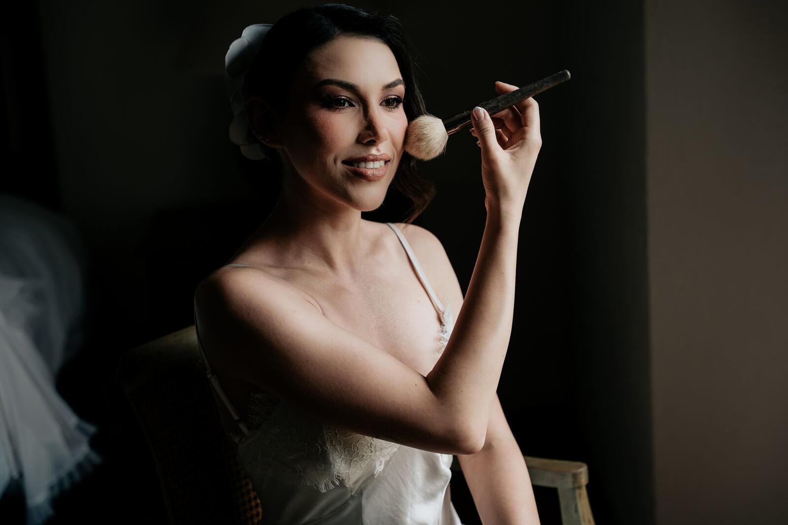 La novia en el maquillaje, con luz dramática y fondo oscuro