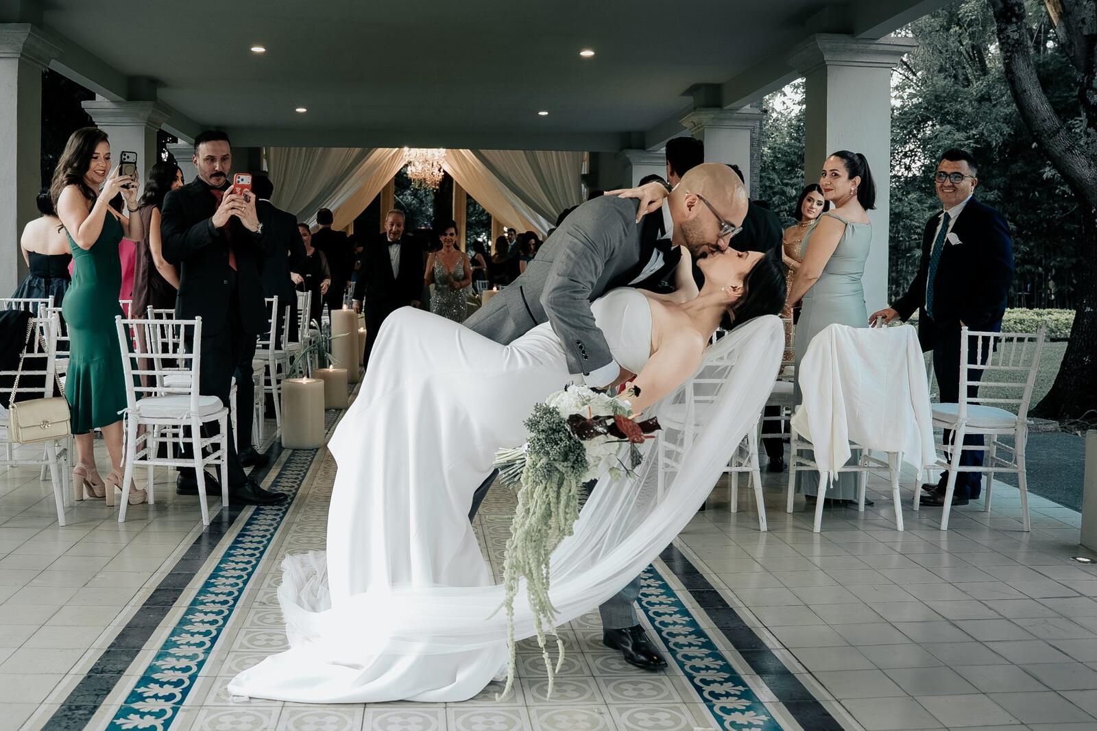 El novio inclina a la novia en el pasillo de la ceremonia frente a los invitados