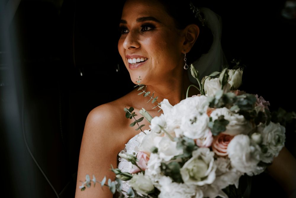 Novia sonriendo con un ramo de rosas blancas