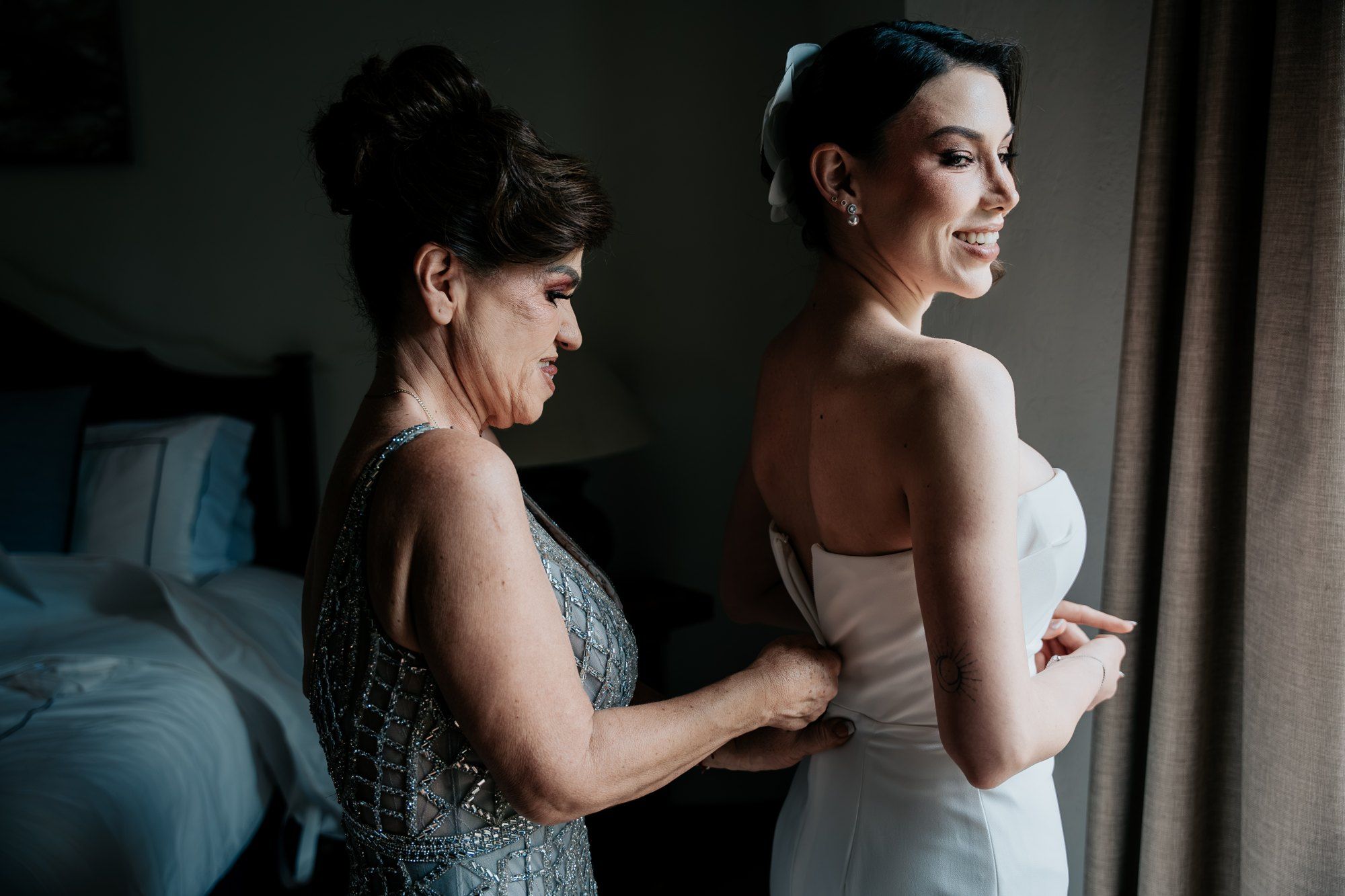 La mamá abrocha el vestido de la novia